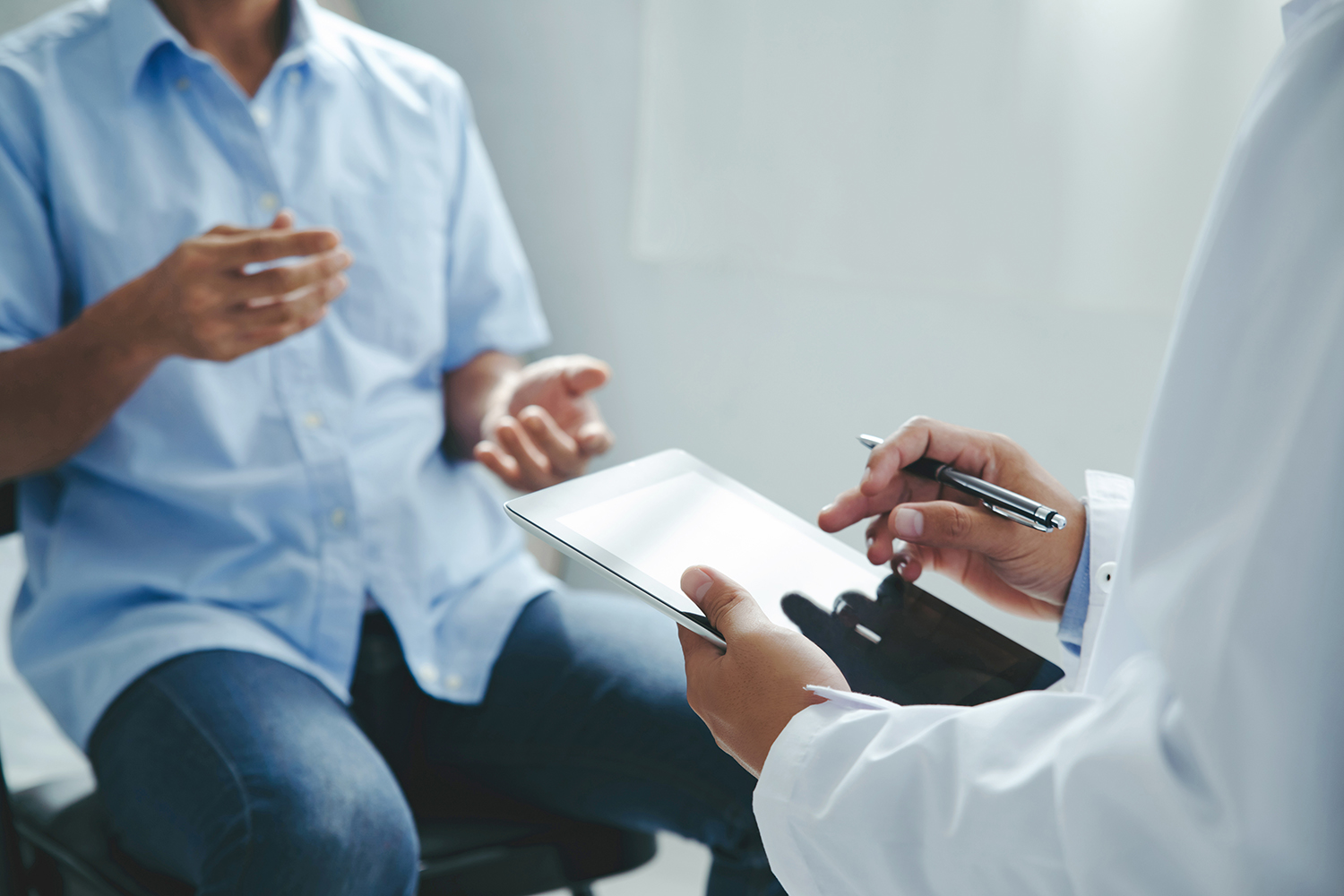 A doctor talks to a patient sitting on the edge of an exam table.